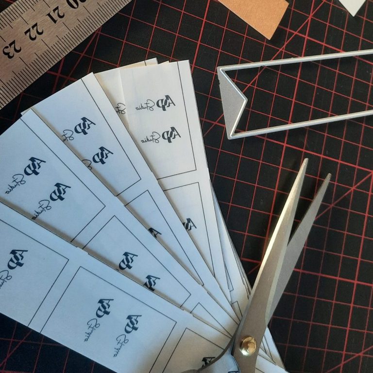 Selbst hergestellte Produktetiketten Schere, Lineal und gestanzte Etiketten auf einem Basteltisch.